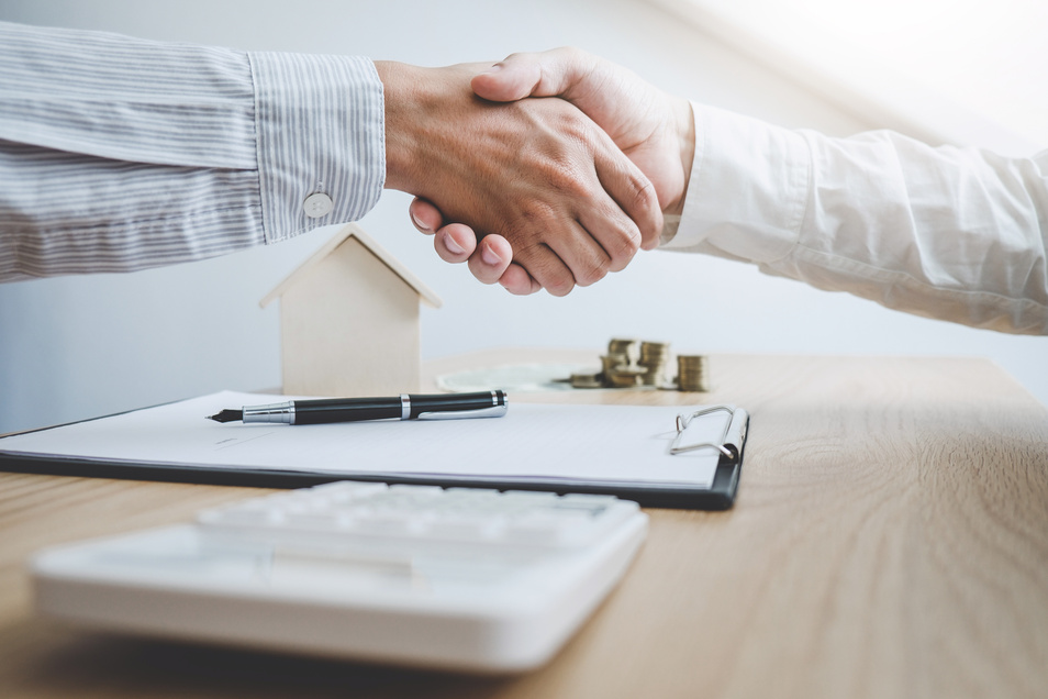 Real estate broker agent and customer shaking hands after signing contract documents for ownership realty purchase, Concept mortgage loan approval